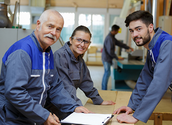 Three workers in a factory setting, symbolizing the benefits of phased retirement programs in labor-intensive jobs.
